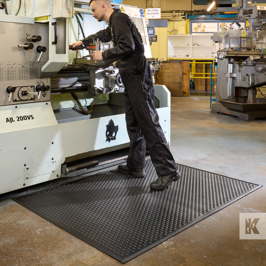 Kleen-Coil - Man operates a lathe machine while standing on an anti-fatigue mat