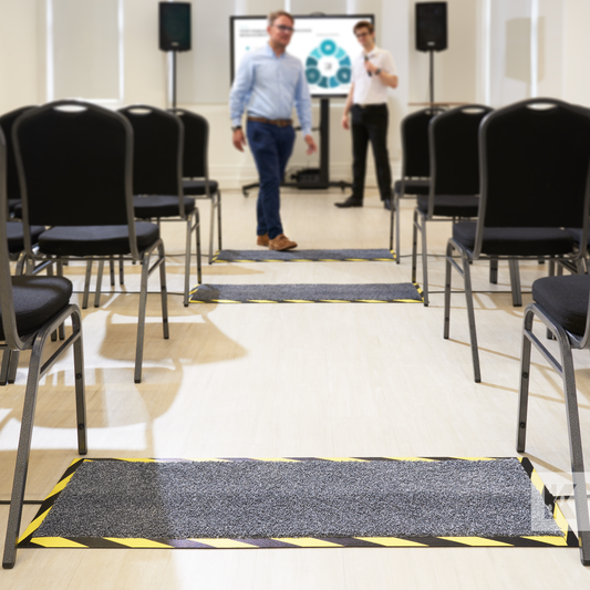 Kleen-Cable Mat - Conference room with rows of seats and two staff members, a cable mat is in the foreground