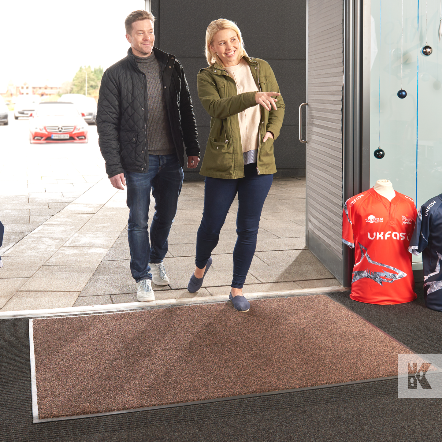 Iron-Horse - Man and woman entering a sports store walking over a brown Iron-Horse mat