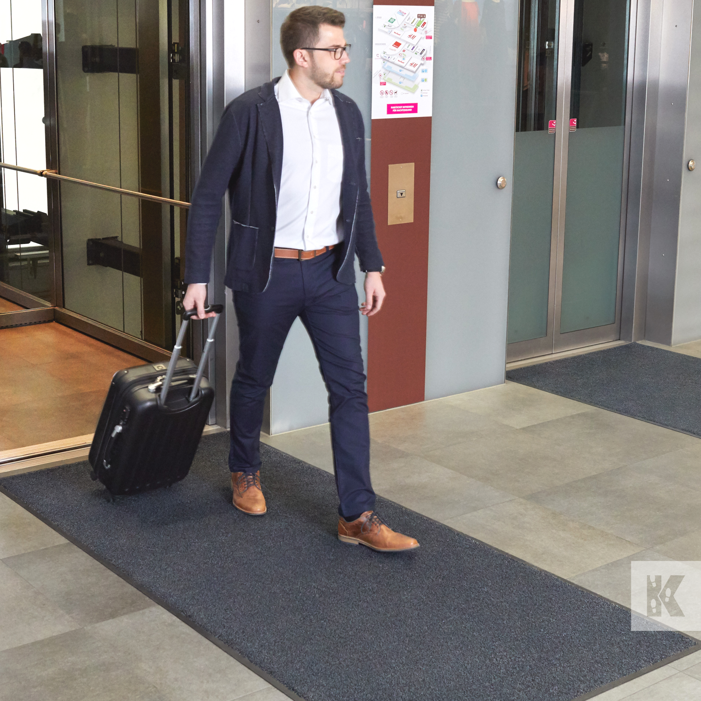 Iron-Horse - Man dragging a suitcase out of a lift across a dark grey Iron-Horse mat