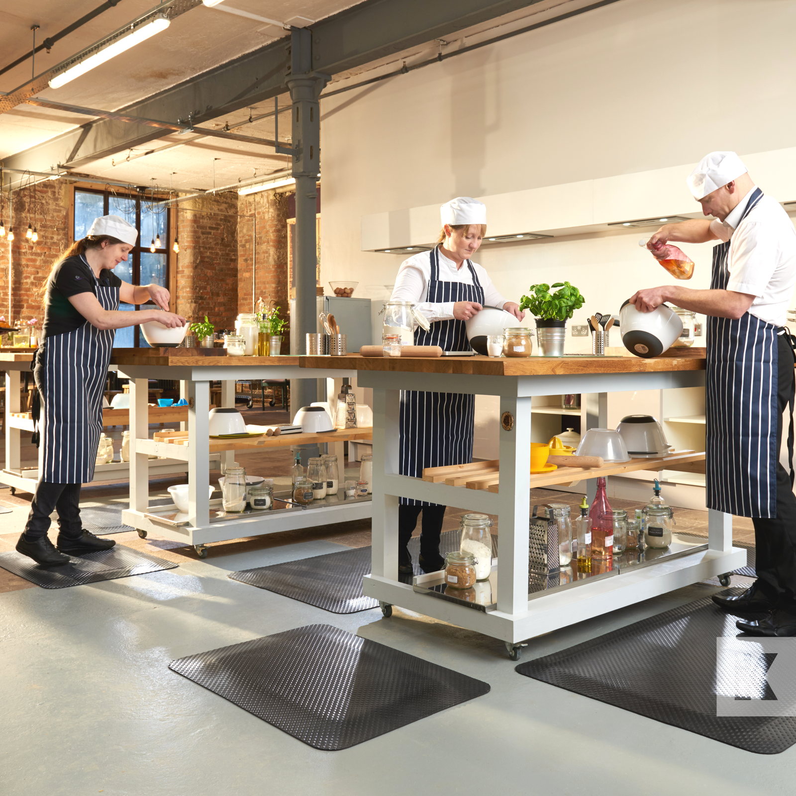 Kleen-Comfort Standard - Professional kitchen scene with three chefs hard at work at their benches preparing food, they are all standing on anti-fatigue mats