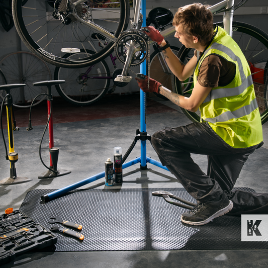 Kleen-Comfort Standard - Man works on bicycle mechanism, kneeling on an anti-fatigue rubber mat with tools