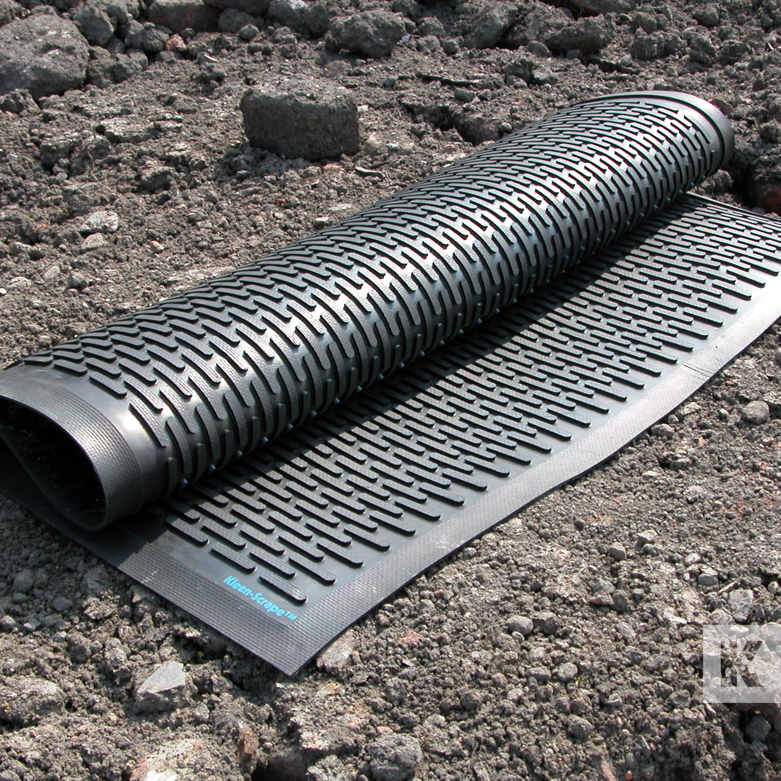 Kleen-Scrape - Heavy duty rubber mat, rolled up and displayed outdoors on some rough dirt terrain