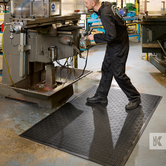 Kleen-Scrape - Man in an industrial setting uses a lathe whilst standing on a solid rubber mat