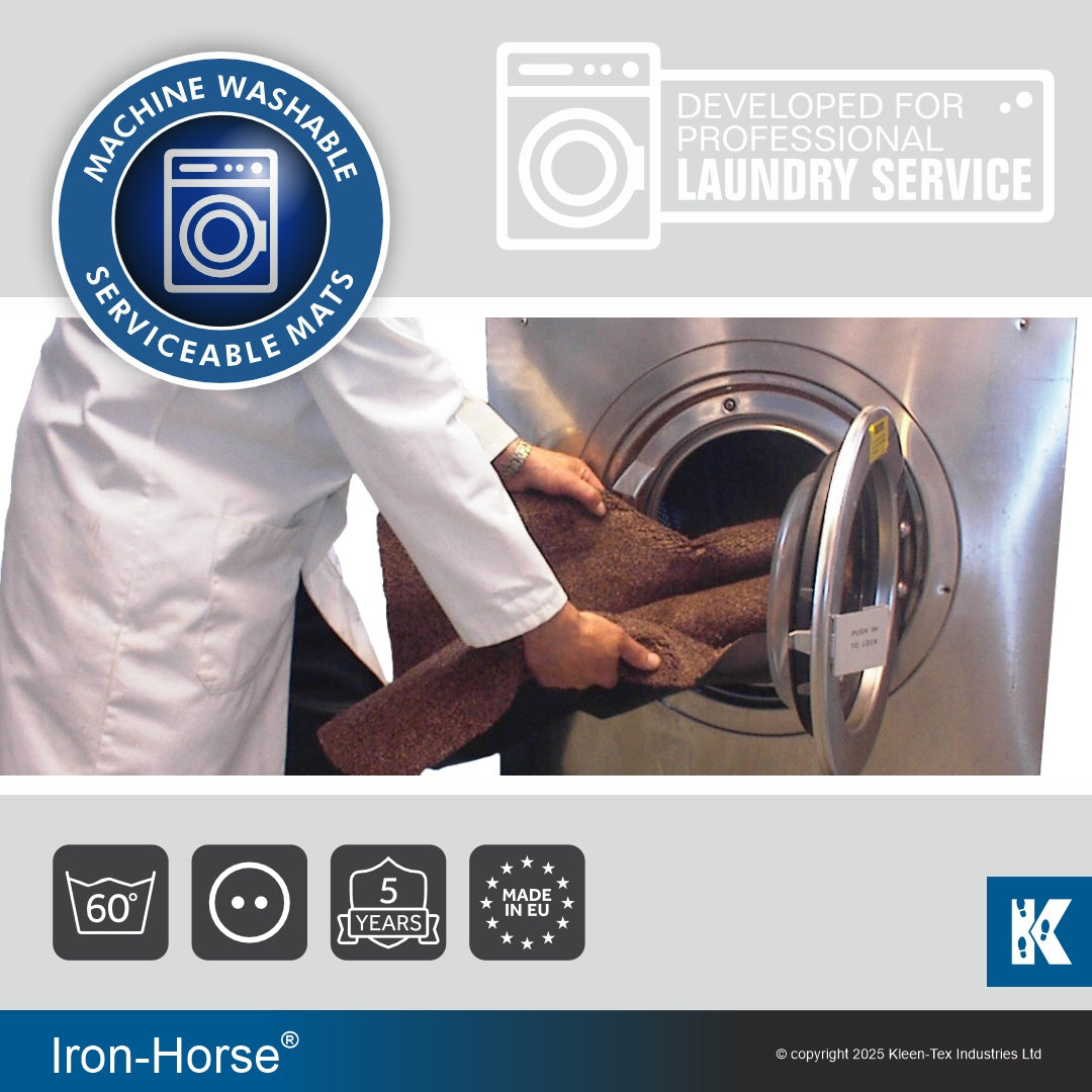 Technician unloading an Iron-Horse mat from a washing machine with wash labels displayed.