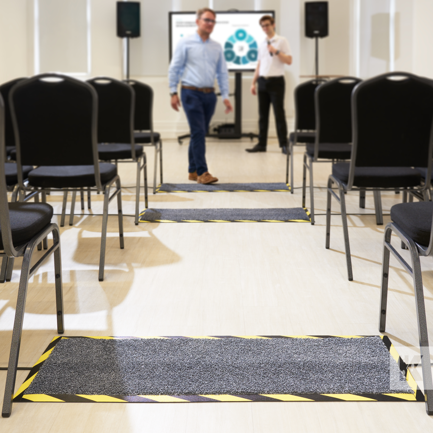 Kleen-Cable Mat - Conference room with rows of seats and two staff members, a cable mat is in the foreground